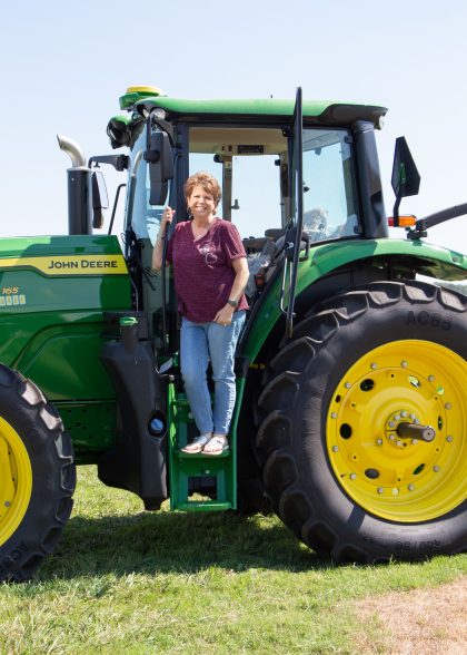 Woman standing by a John Deere tractor